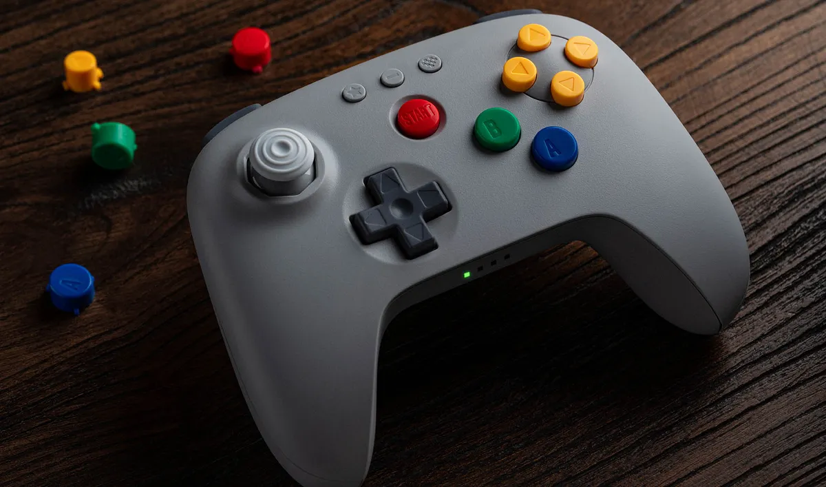 Grey 8BitDo 64 2.4G wireless controller with colored N64-style buttons on a wooden table
