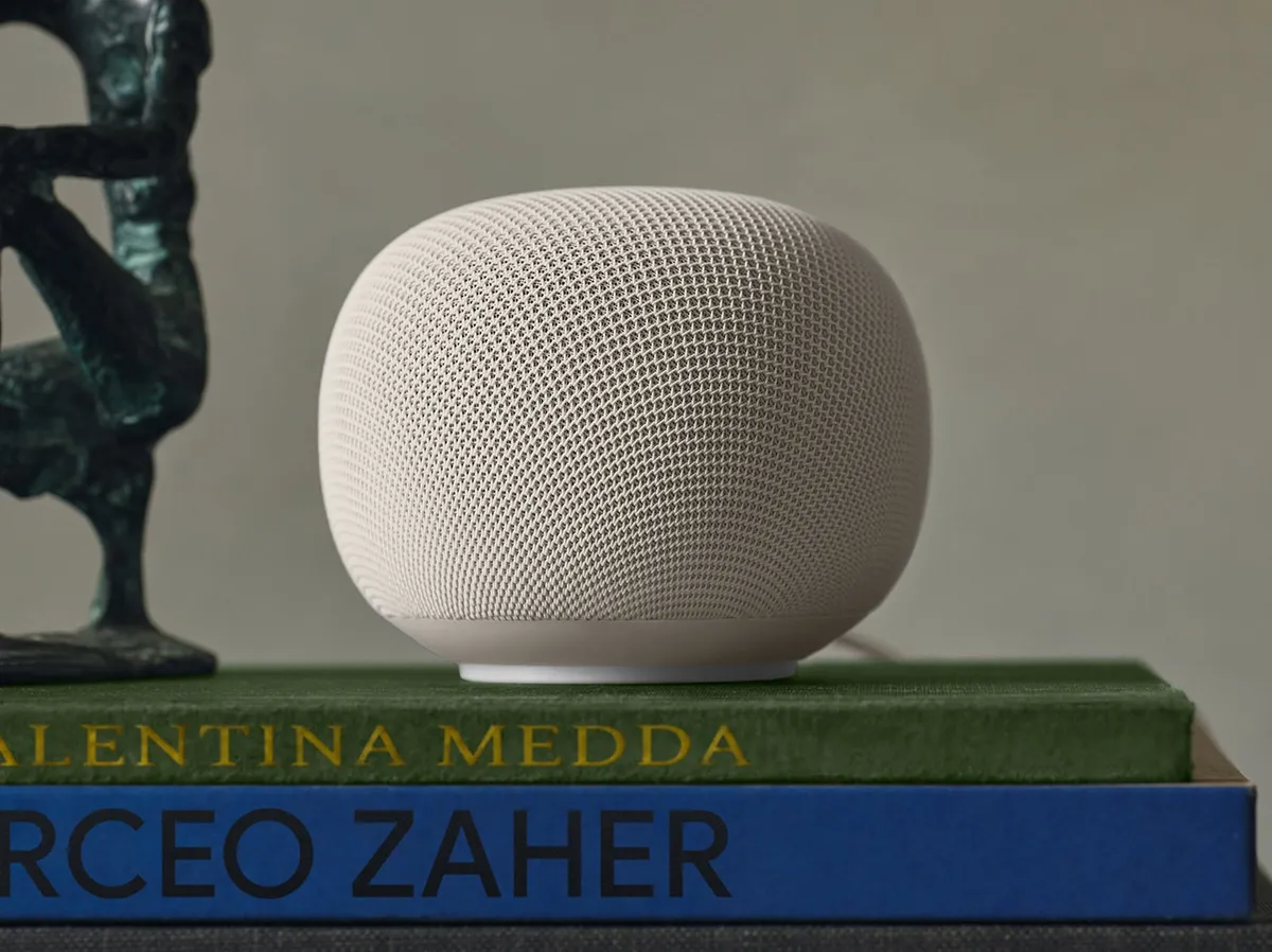 Google Home Speaker in Porcelain, a round fabric-covered speaker sitting on a stack of books
