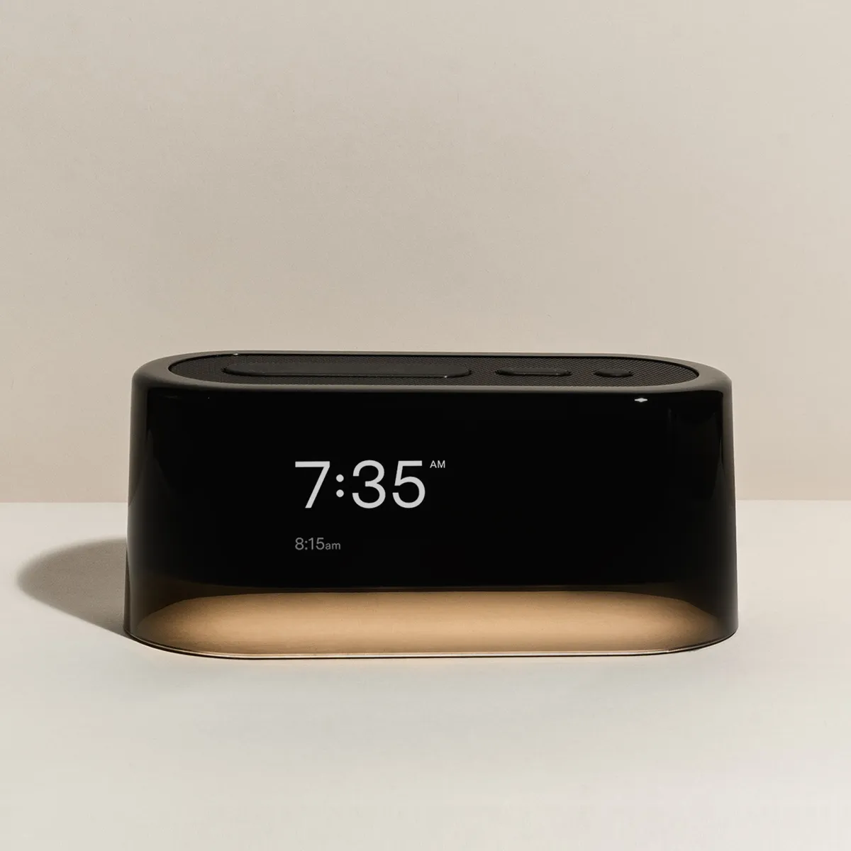 Loftie Clock in black, a rounded oblong alarm clock showing 7 with a warm glowing base
