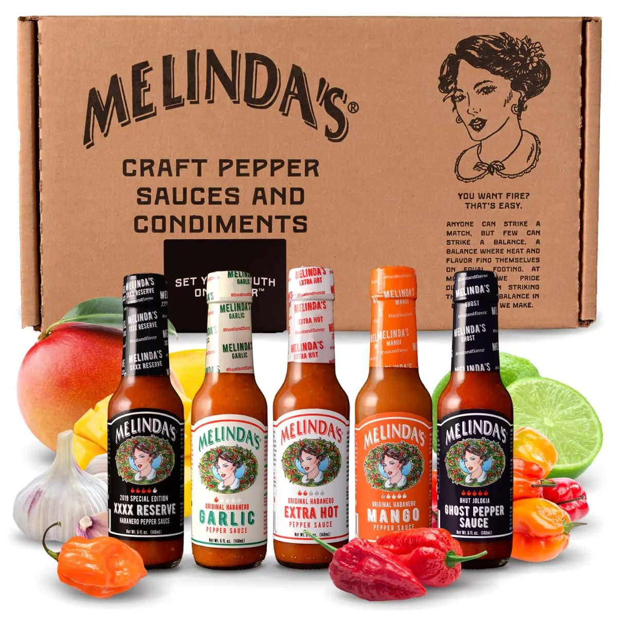 Five Melinda's hot sauce bottles: XXXX Reserve, Garlic, Extra Hot, Mango and Ghost Pepper, in front of the gift box