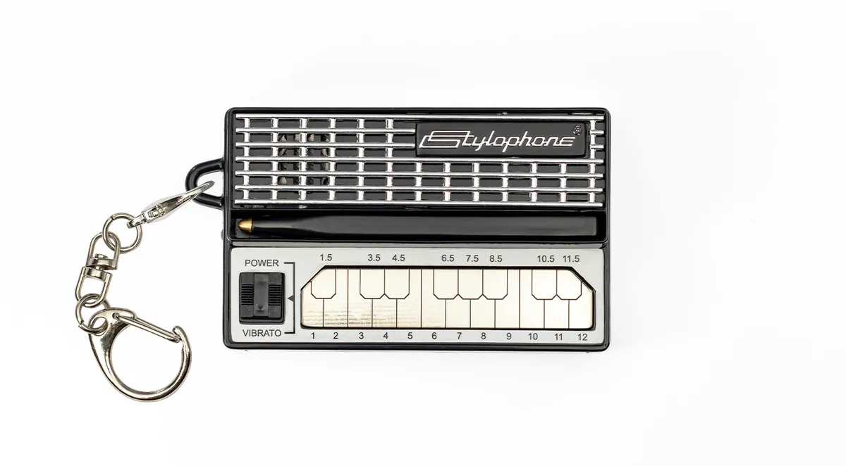 The Stylophone Mini in black with its silver metal keyboard, stylus and keychain